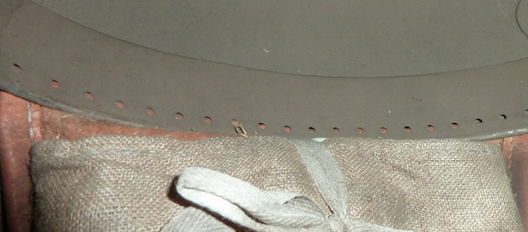 Cerclage métallique troué au niveau de chaque patte de coiffe, patte de coiffe maintenue coincée sans couture.