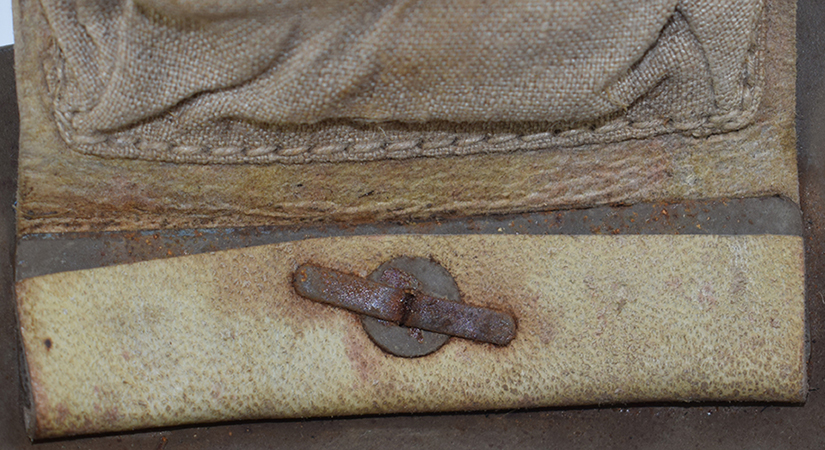 Patte de coiffe maintenue par une plaque métallique, maintien renforcé d'une rondelle.