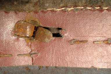 Fixation latérale à la coque entourée des agrafes retenant le liège. Fixation latérale à la coque entourée des agrafes retenant le liège.