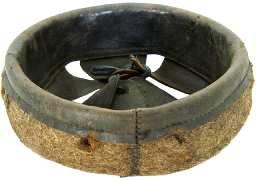 Coiffe après-guerre, repliée (recto), coutures et perforations des agrafes crampons. Coiffe après-guerre, repliée (recto), coutures et perforations des agrafes crampons.