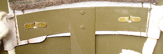 Patte de coiffe maintenue par deux attaches parisiennes.