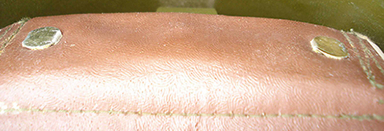 Patte de coiffe maintenue par deux attaches parisiennes.