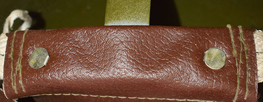 Patte de coiffe maintenue par deux attaches parisiennes.